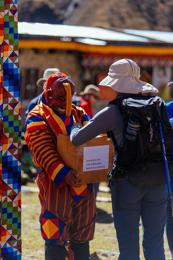 Atsara collecting a donation box from a trekker at the Jomolhari Mountain Festival