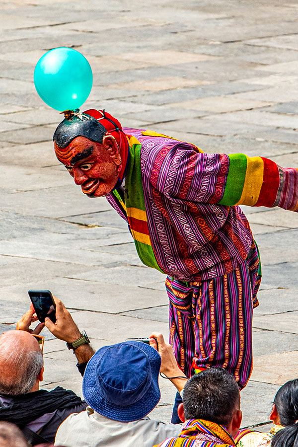 Atsara with a balloon on his head bowing to spectators taking photos
